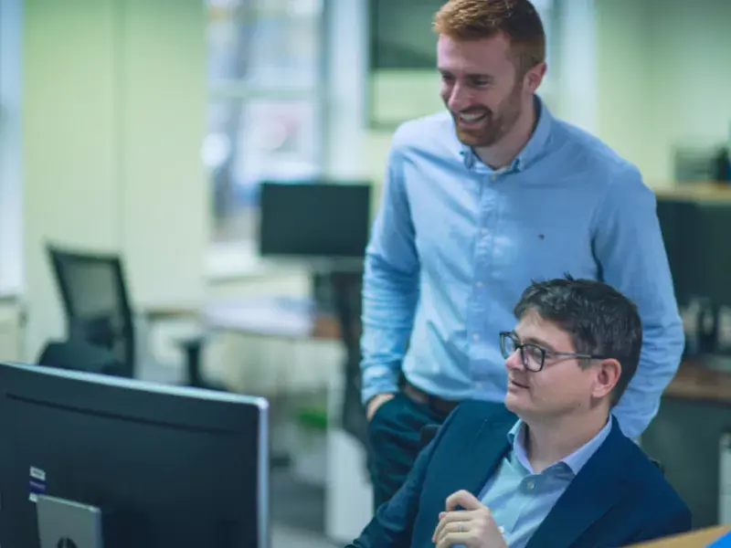 Two YTL Developments employees smiling and looking at a computer screen