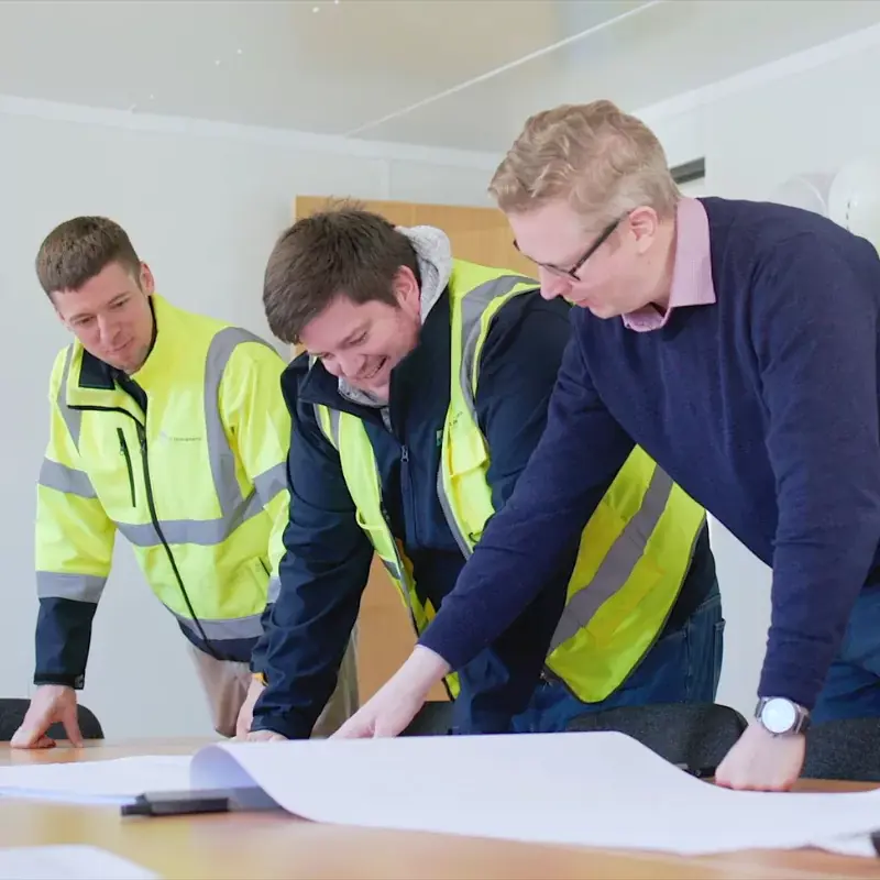 Three YTL employees looking over some plans and smiling